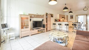 Ein modernes Wohnzimmer mit Fernseher, Sitzgelegenheiten und einem Essbereich.