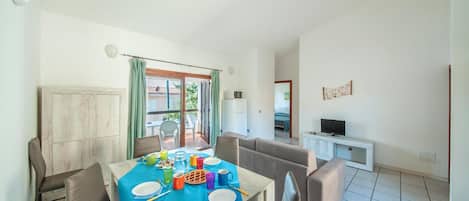 A dining area with a table set for four, a sofa, and a TV in the background.