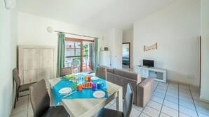 Un coin repas avec une table dressée pour quatre personnes, un canapé et un téléviseur en arrière-plan.