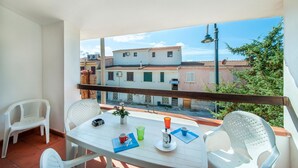 Un balcon avec une table blanche, des chaises et une vue sur les immeubles.