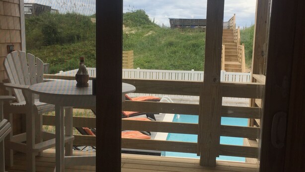 Een houten terras met een zwembad, ligstoelen en een tafel.