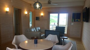 Een modern interieur met een ronde tafel en witte stoelen, houten wanden en een plafondventilator.