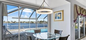 Enjoy breathtaking views of the water from the balcony, featuring a pool and lounge chairs.