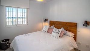 A bedroom with a bed, a window with bars, a ceiling fan, and a wall-mounted lamp. - Nice apartment in Mijas Costa with swimming pool (Mijas Costa)