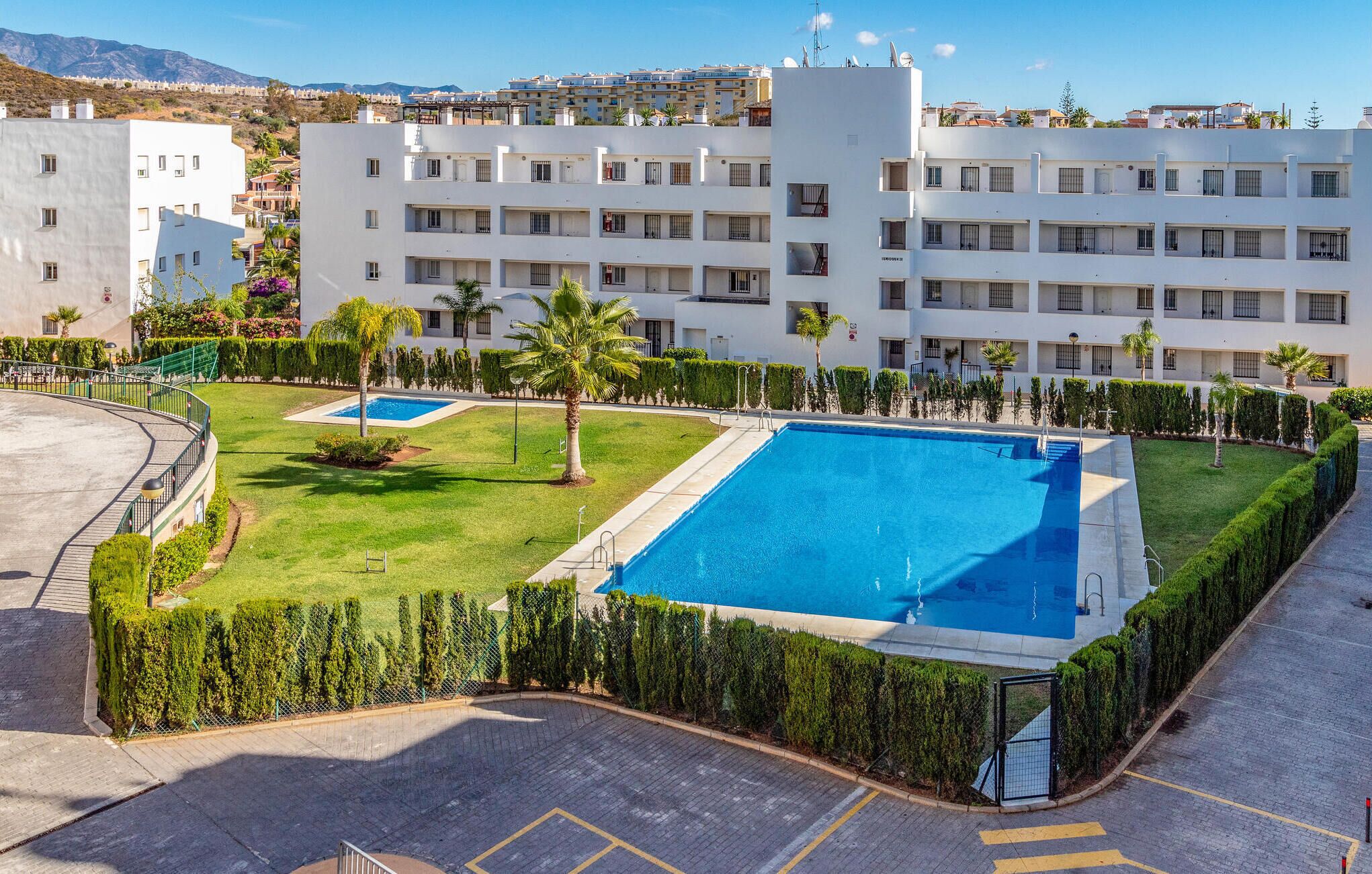 Un hôtel composé de plusieurs bâtiments blancs, doté d’une piscine centrale et de pelouses verdoyantes bien entretenues.
