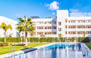 A modern hotel with a swimming pool, surrounded by well-maintained lawns and palm trees. - Nice apartment in Mijas Costa with swimming pool (Mijas Costa)