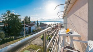 Un balcone con ringhiera metallica che si affaccia su una zona residenziale e un corpo d'acqua.
