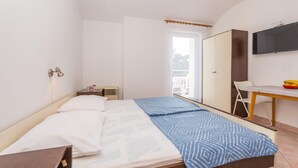 Una camera da letto con un letto, una scrivania, una sedia, un armadio e una televisione.