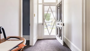 A hallway with a white door leading outside, a dark wall on one side, and a carpeted floor. - Devitt on French is a quiet, romantic stone cottage in Angaston, Barossa Valley (Angaston)