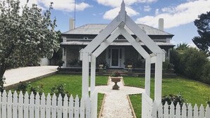 A white picket fence leading to a house with a triangular entrance archway. - Devitt on French is a quiet, romantic stone cottage in Angaston, Barossa Valley (Angaston)