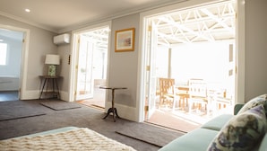 A spacious living area with a sofa, a small table, and a lamp. There is a door leading to an outdoor patio with chairs and a table. - Devitt on French is a quiet, romantic stone cottage in Angaston, Barossa Valley (Angaston)