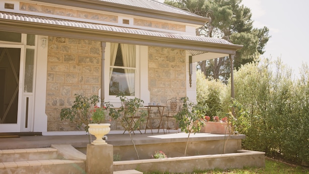 A stone house with a covered porch, outdoor seating, and potted plants. - Devitt on French is a quiet, romantic stone cottage in Angaston, Barossa Valley (Angaston)