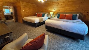 A log cabin room with two beds, a desk, and a chair.