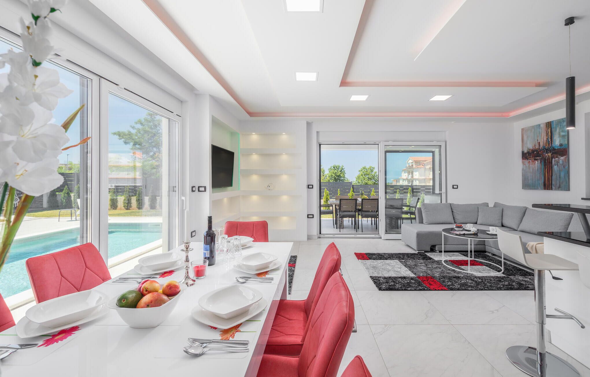 A modern living room with a dining area, large windows, and a pool view.