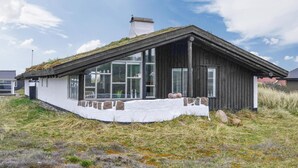 Une maison moderne avec un toit en pente, de grandes fenêtres et une base en pierre.