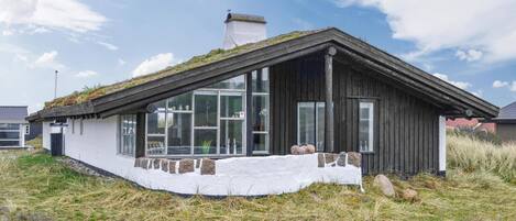 A modern house with a sloped roof, large windows, and a stone base.