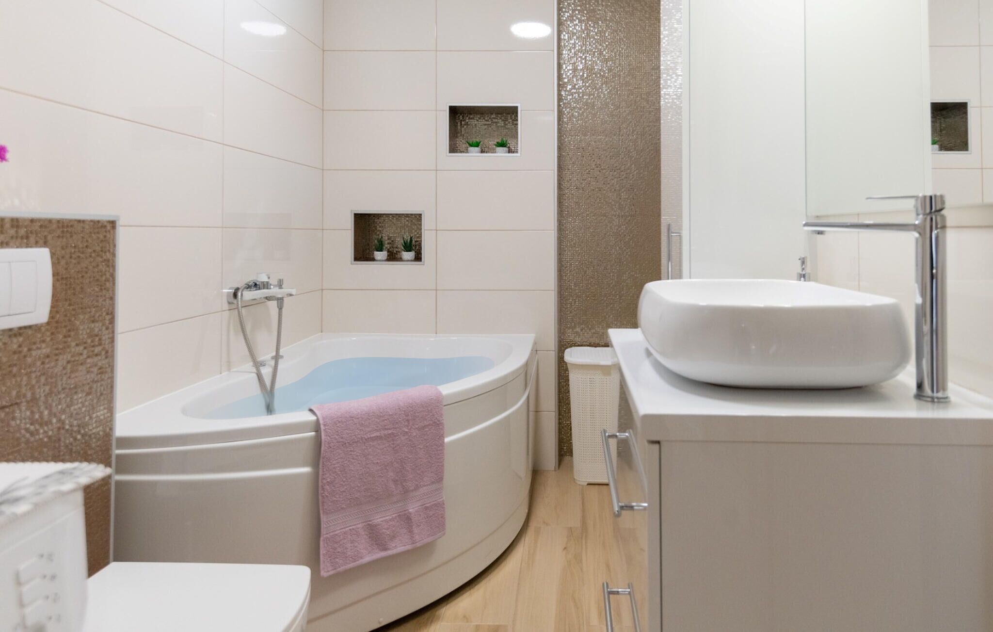 Een moderne badkamer met een vrijstaand bad, een witte wastafel en een spiegel.