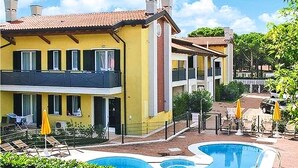 Ein gelbes Gebäude mit Schwimmbad, überdachter Terrasse und einem eingezäunten Bereich mit Liegestühlen.