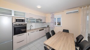 Cocina compacta con microondas, horno y lavabo. Hay una mesa de comedor con sillas y una ventana con vistas.