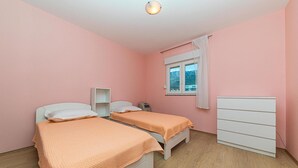 Un dormitorio con dos camas, una ventana con vistas y un aparador blanco.