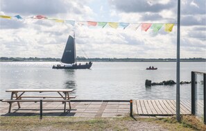 En picknickplats vid sjön, med en segelbåt och en roddbåt som ligger i vattnet.