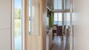 A narrow corridor leading to a dining area with a view of water. - Amazing ship in Biddinghuizen with house sea view (Biddinghuizen)