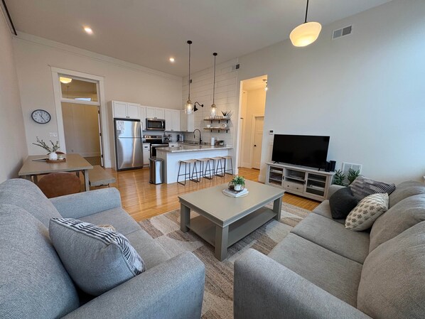 A modern living room with a sofa, coffee table, and a TV. - Loft on Lincoln Hancock #204 (Hancock)