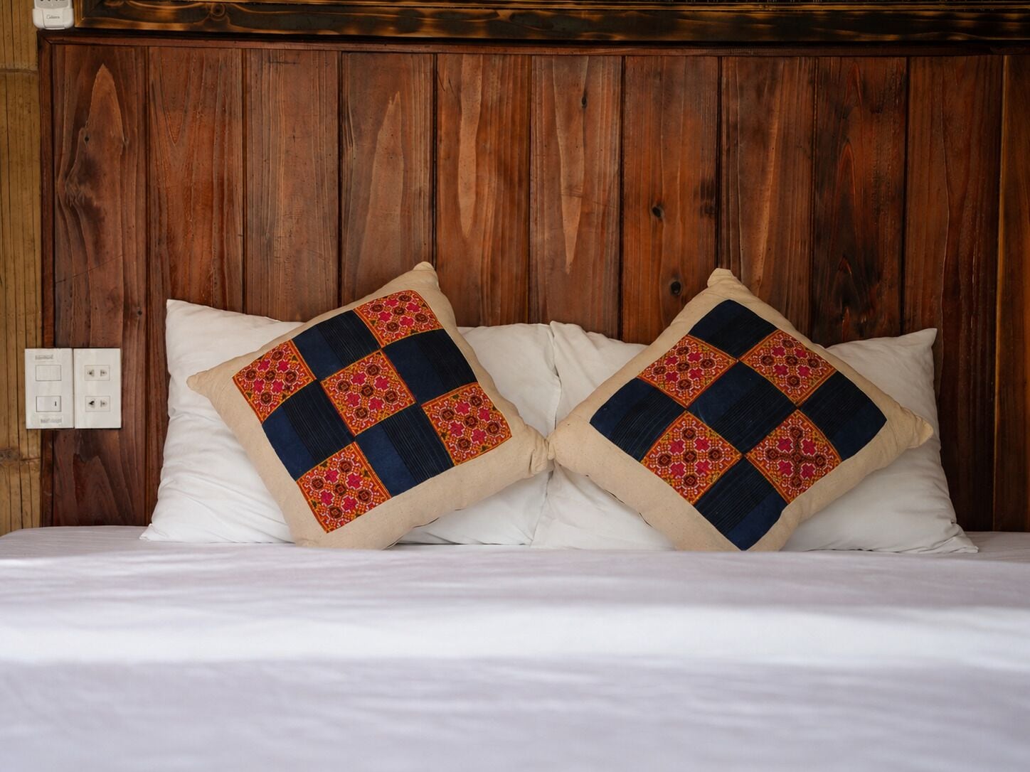 A bed with two pillows featuring a geometric pattern.