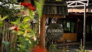 A rustic wooden sign for Pu Hmong Eco Retreat, surrounded by greenery and potted plants. - Pu Hmong Eco Retreat (Sa Pa)