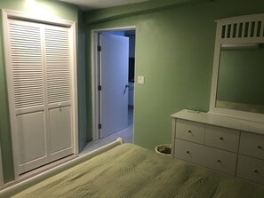 A bedroom with a bed, a dresser, a mirror, and a closet.