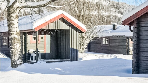 Een houten hut met een sneeuwbedekte dak en een klein terras.