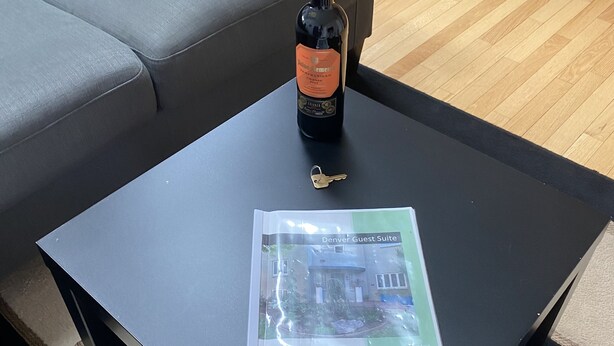Eine Weinflasche auf einem schwarzen Tisch mit einer Broschüre und einem Schlüssel.