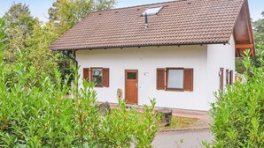 A white building with a tiled roof, two windows with shutters, and a door.