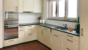 A kitchen with white cabinets, a black countertop, and a window above the sink. - Fifinhaus 1. OG Süd by Interhome (Fiesch)