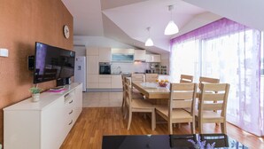 Una cucina moderna con mobili bianchi, forno integrato e zona pranzo con sedie di legno e tavolo in vetro.