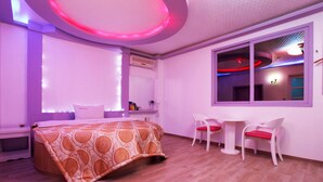 A modern bedroom with a bed, bedside tables, a window, and a small seating area with chairs. - Whitehouse Motel (Seosan)