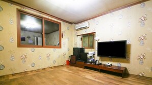 A room with wooden flooring, a large window, a television mounted on the wall, and a small table with a chair. - Whitehouse Motel (Seosan)