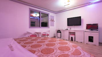 Ein Schlafzimmer mit Bett, Schreibtisch, Stuhl, Fernseher und Fenster.