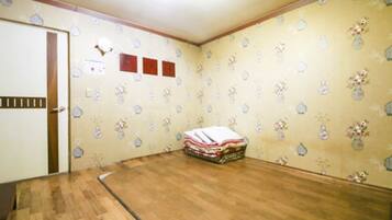 A room with wooden flooring, a door with a striped pattern, and a wall with a floral wallpaper pattern.