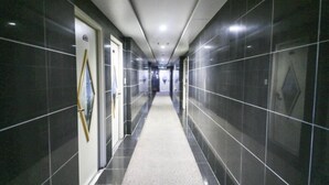 A corridor with dark tiled walls and a carpeted floor. - Whitehouse Motel (Seosan)