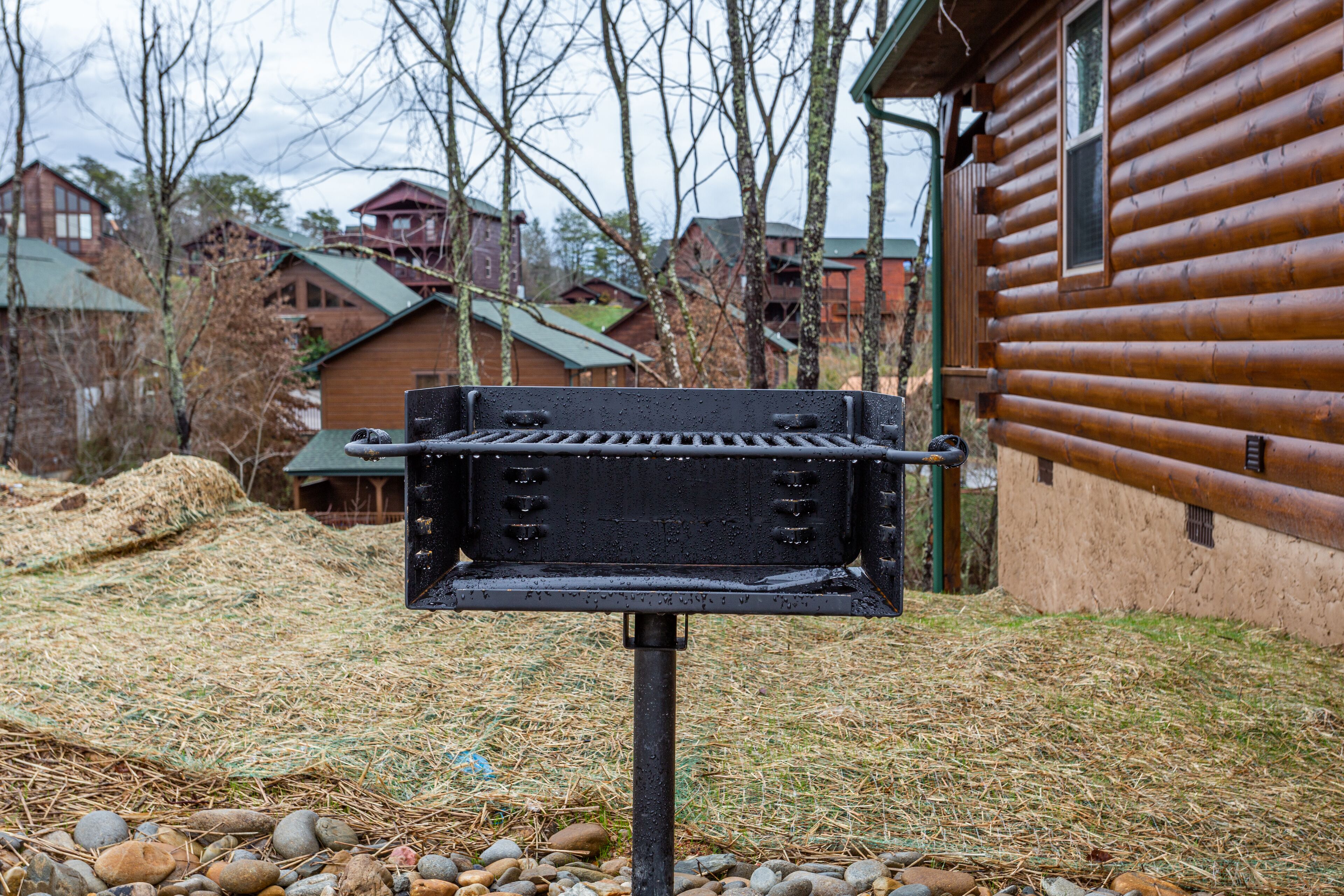 A grill in a backyard with a wooden cabin in the background.