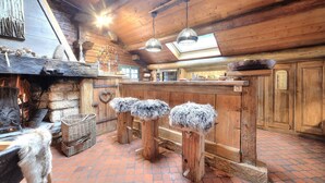 A rustic wooden interior with a fireplace, stone walls, and a brick floor. - Authentic, warm, luxurious chalet, swimming pool, jacuzzi, sauna and fireplace (Les Contamines-Montjoie)