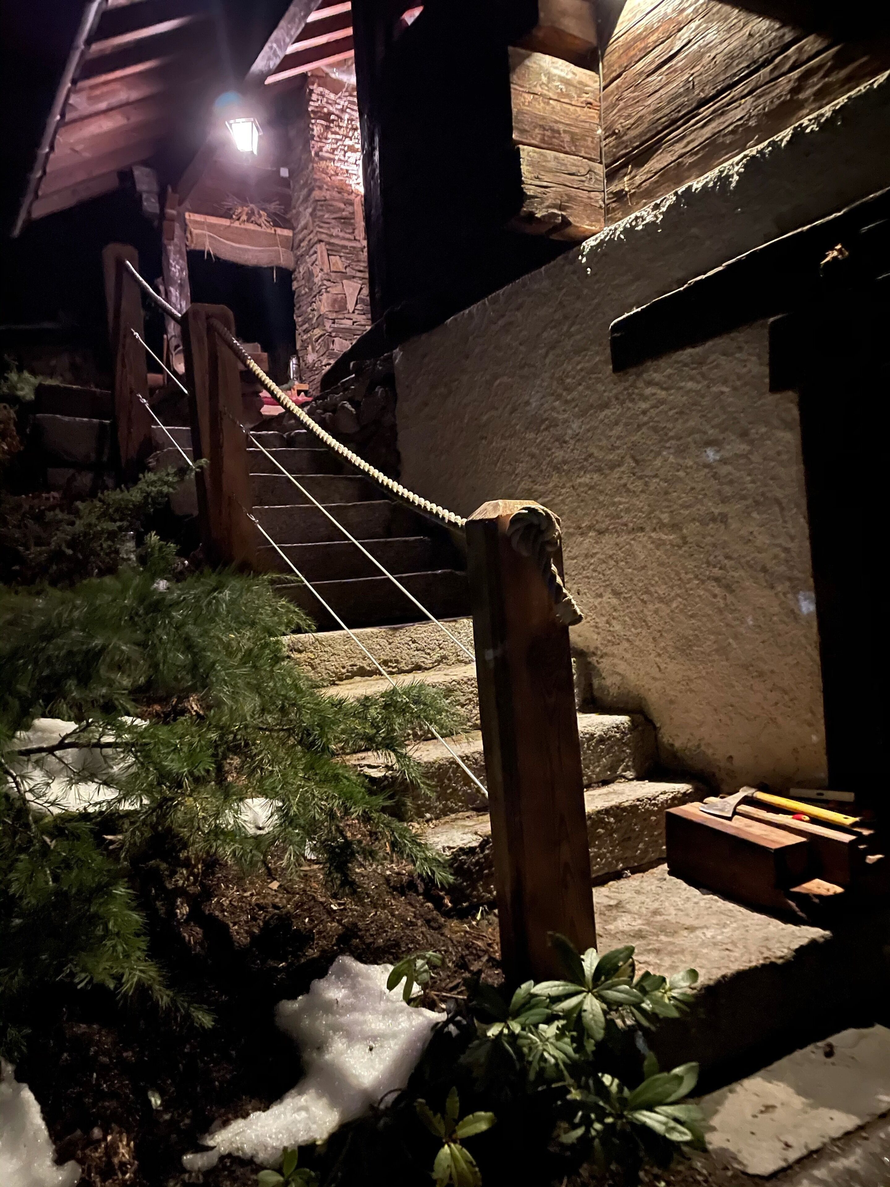 Eine Holztreppe führt zu einem Gebäude mit einer Steinaußenwand.