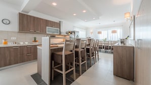 Une cuisine moderne avec des meubles en bois, un îlot central doté de chaises et un coin repas avec une table et des chaises.