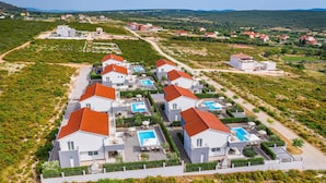 Un quartier résidentiel avec des maisons modernes, chacune dotée d’une piscine et d’un toit recouvert de tuiles rouges.