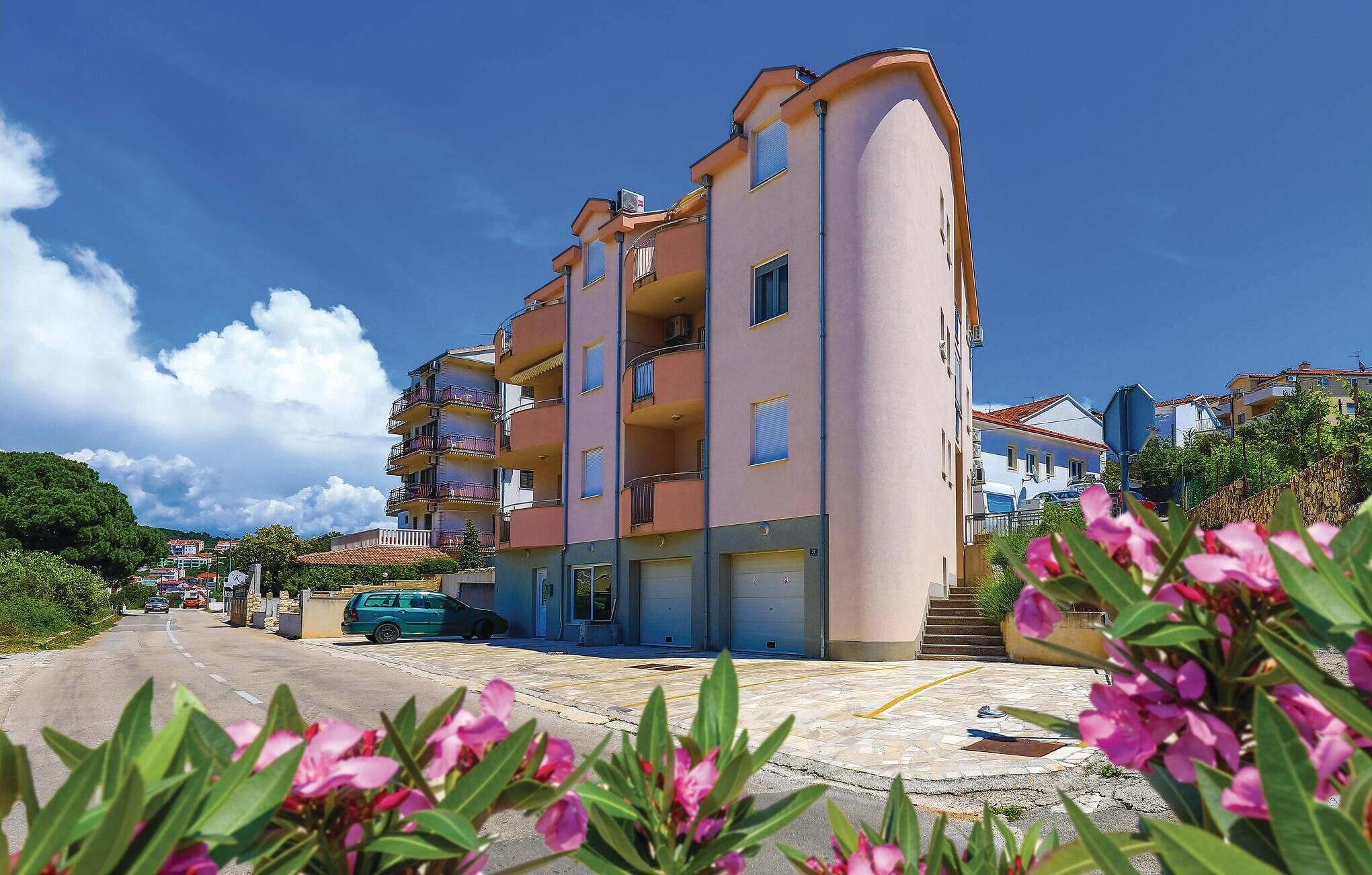 Um edifício residencial com várias andares, varandas, área de estacionamento e céu claro.