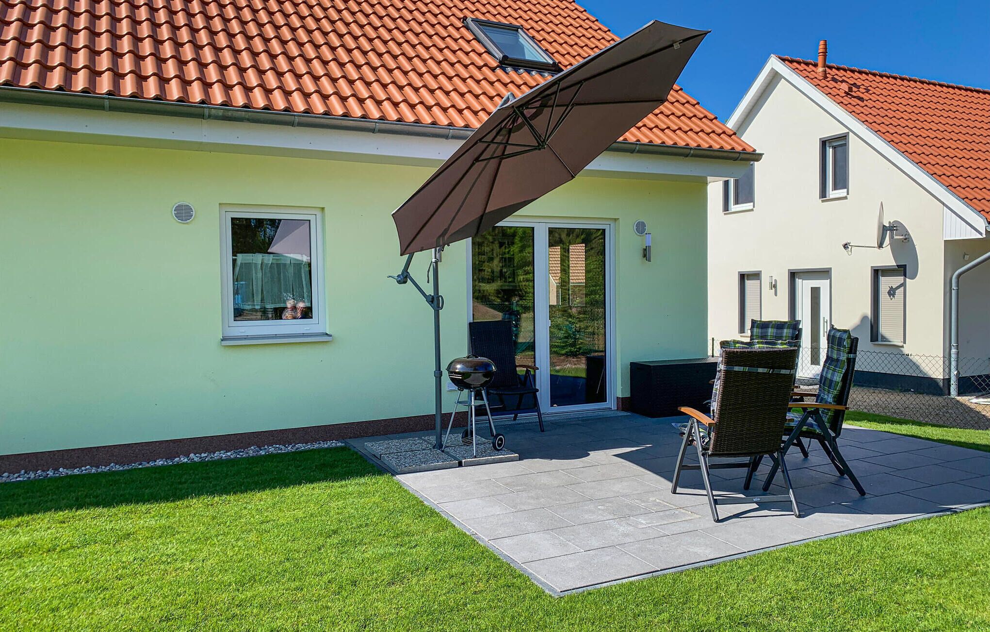 Une maison dotée d’un patio comprenant deux chaises et une table, une porte-fenêtre coulissante et une antenne parabolique.