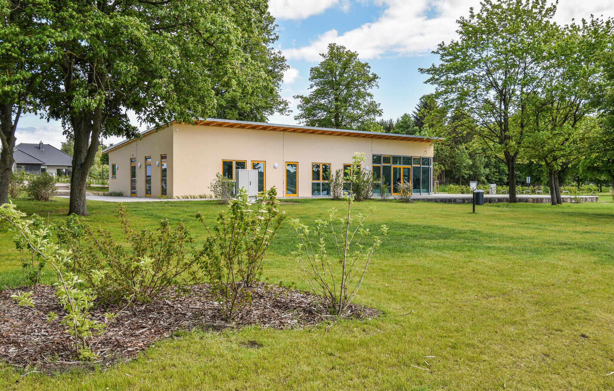 A modern building with a flat roof, large windows, and a well-maintained lawn.