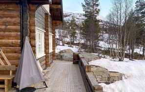 Una baita di legno con veranda e zona barbecue coperta.
