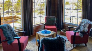 A room with large windows, two red chairs with fur throws, a small table, and a view of the outdoors. - Pet friendly home in Hovden I Setesdal (Hovden I Setesdal)